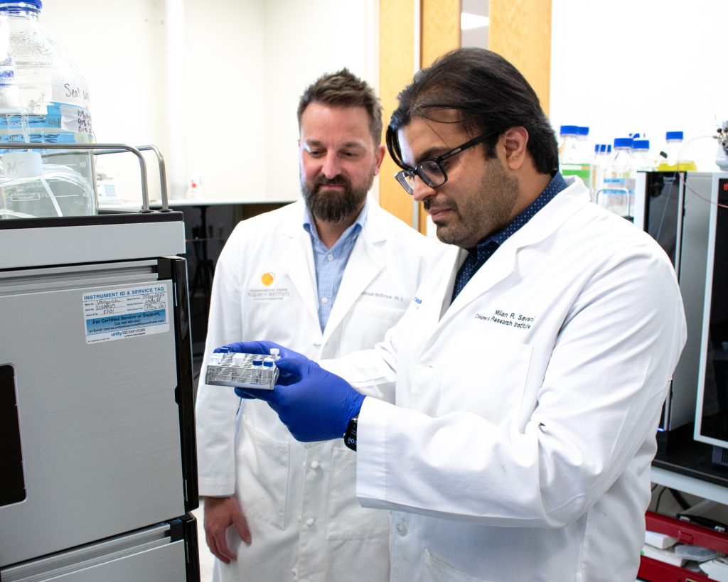 Sam McBrayer, Ph.D., (left) watches as Milan Savani, Ph.D., loads samples in CRI Metabolomics Shared Facility.