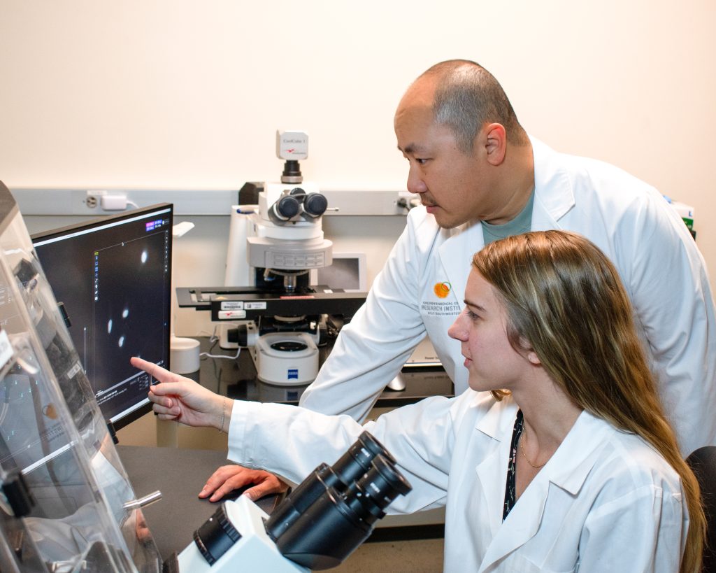 Peter Ly, Ph.D., Assistant Professor in Children's Medical Center Research Institute at UT Southwestern and of Cell Biology, Pediatrics, and in the Harold C. Simmons Comprehensive Cancer Center, observes microscope images with Ly Lab researcher Elizabeth Maurais, Ph.D., a recent graduate of the Genetics, Development and Disease Program at UT Southwestern.
